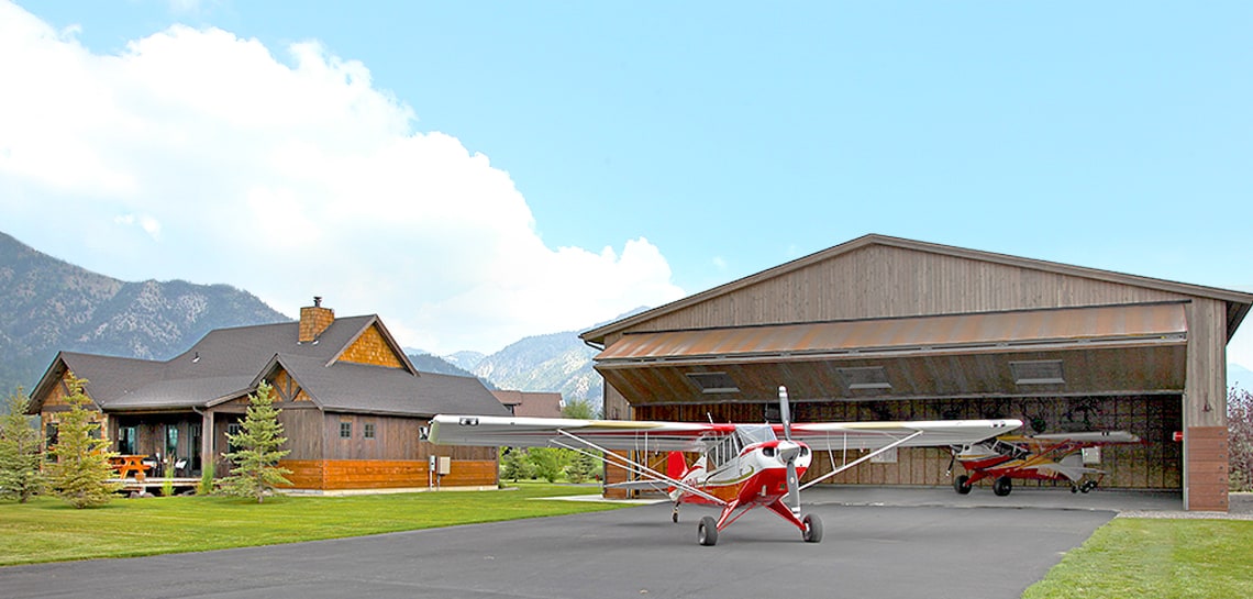 red and white plane in front of bifold door on a hangar