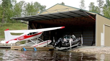 A happy owner uses Schweiss Hydraulic Door to store plane and boat